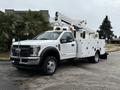 A 2018 Ford F-550 truck with a white utility body and an elevated bucket lift for work at height