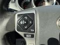Close-up of a steering wheel control panel from a 2015 Toyota Tacoma featuring directional buttons and a mode selector