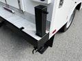 A 2016 Ford F-550 with a white body featuring a black hitch on the rear and a textured silver step plate