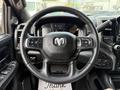 Steering wheel of a 2024 RAM 2500 featuring the RAM logo with control buttons and a textured grip