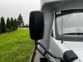 A close-up of the side mirror of a 2015 Chevrolet Express van with droplets of water on its surface