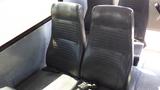 Two black leather bus seats with vertical grooves positioned next to each other