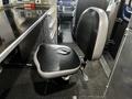 A black and gray swivel office chair with a padded seat and backrest positioned next to a metal work surface in a vehicle interior