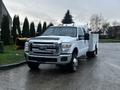 A 2014 Ford F-350 SD truck with a white body and black accents is parked, featuring a flatbed and toolboxes on the sides