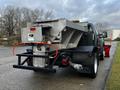 A 2012 Ford F-550 truck with a silver metal salt spreader attached to the rear and a black bumper with red reflectors