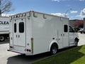 A white 2013 Chevrolet Express ambulance with a high roof and rear doors featuring an emergency medical symbol