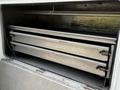 A 2016 Ford F-550 with a sliding compartment featuring three folded metal shelves arranged inside a service body