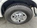 A close-up of a chrome wheel of a 2014 Chevrolet Express with a rugged tire tread showing the tire size and brand markings
