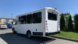 A white 2011 Chevrolet Express shuttle bus with large windows and a rear ramp for accessibility