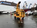 A yellow 1993 Bandit 200 wood chipper with a large chute and a hydraulic feeding mechanism positioned on wooden pallets