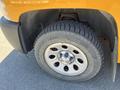 A close-up of a tire on a 2013 Chevrolet Silverado 1500 showing a silver wheel with a Chevrolet logo and a rugged tread pattern