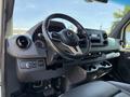 Interior view of a 2019 Mercedes-Benz Sprinter showing the steering wheel dashboard and center console with storage compartments