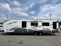 A 2013 Outdoor Wind River travel trailer with a sleek design featuring a white exterior and dark accents, includes multiple windows and two axles for support