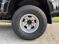Close-up of a tire from a 2021 Ford F-350 SD showing a rugged tread pattern and a silver alloy wheel with multiple lug holes