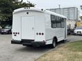 A white 2020 Chevrolet Express bus with large side windows and a rear door visible from the back angle