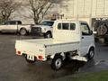 A white 2008 Suzuki Carry with a flatbed and a compact cab is parked, featuring a simple design and small wheels