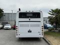 A white 2018 Grande West Vicinity bus viewed from the rear with a distinctive exhaust pipe and taillights visible