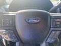 Steering wheel of a 2017 Ford F-150 featuring the Ford emblem and various controls for audio and cruise settings