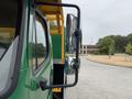 A green 2015 Freightliner M2 106 truck is pictured with its side mirror visible in the foreground