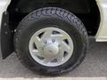 A silver wheel of a 2004 Ford Econoline with a black rugged tire labeled Outpost AT
