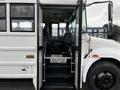 A 2013 International 4200 bus with an open entrance displaying steps and an interior view showing the driver's seat and dashboard