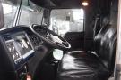 Interior view of a 2015 Kenworth T660 with a black leather driver's seat and dashboard featuring gauges and controls