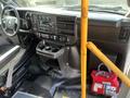 Interior of a 2018 Chevrolet Express showing the driver’s seat dashboard control panel and storage compartments with a fire extinguisher and a bag visible nearby