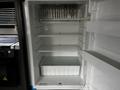 An open refrigerator with multiple shelves and a glass container on the bottom shelf in a 2022 Aspen Trail