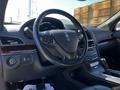 Interior of a 2013 Lincoln MKT featuring a leather steering wheel with controls and a sleek dashboard with wood accents
