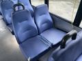 Two blue fabric upholstered seats with a split in the middle positioned on a bus interior