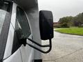 A 2015 Chevrolet Express with a side mirror attached showing a wet surface from rain