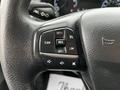 A close-up of the steering wheel controls of a 2020 Ford Transit with buttons for cruise control settings and audio functions