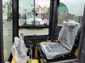 Interior of a 2024 AGT Industrial Yellow H13R Mini Excavator with a plastic-covered seat and control levers visible in the foreground