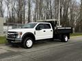 A white 2021 Ford F-550 with a flatbed truck design parked on a pavement