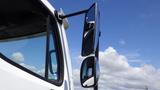 A 2017 Freightliner M2 106 side mirror reflecting the sky with a clear view of the truck cabin window and door