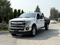 A white 2020 Ford F-350 Super Duty truck parked in a lot with a flatbed and chrome details
