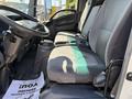 Interior view of a 2013 Isuzu NPR showing two gray upholstered seats with seat belts and a black console between them