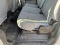 A grey passenger seat in the back of a 2015 Ford F-450 SD with fabric upholstery and a rubber floor mat beneath it