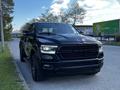 A 2019 RAM 1500 truck with a black exterior and prominent grill parked on a road with trees in the background