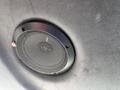 Close-up of a black circular speaker grille mounted on a surface with a textured finish