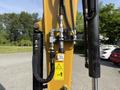 A close-up view of the hydraulic system on a 2022 Caterpillar 306 excavator showcasing valves and warning labels
