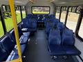 Interior view of a 2019 Chevrolet Express featuring rows of blue seats arranged for passenger transport with a central aisle