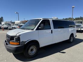 A 2007 Chevrolet Express van with a white exterior and black front grille parked on a lot with a side view showcasing its large windows and simple design