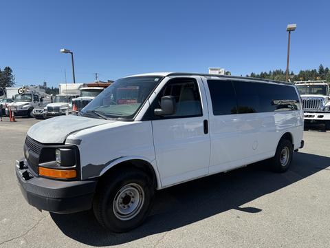 A 2007 Chevrolet Express van with a white exterior and black front grille parked on a lot with a side view showcasing its large windows and simple design