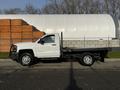 A white 2017 Chevrolet Silverado 3500HD flatbed truck parked with no cargo on a flatbed and visible wheels and headlights