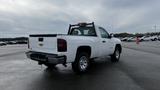 2013 Chevrolet Silverado 1500 in white with a pickup bed and chrome wheels parked at a lot