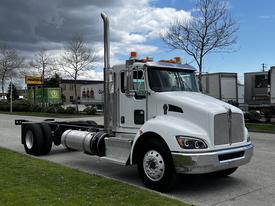 A white 2014 Kenworth T370 truck with a shiny chrome grille and a tall exhaust stack parked on the street
