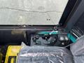 Interior controls of a 2024 AGT Industrial Green QH13R Mini Excavator featuring joystick levers switches and storage box