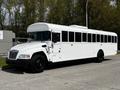 A 2022 Blue Bird BB Conventional school bus painted white with large windows and black wheels estacioned on a paved surface