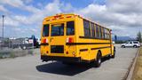 A yellow 2014 Freightliner Thomas diesel school bus viewed from the rear with black stripes and windows